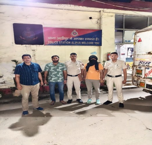 Police personnel and a face-covered man outside Alipur police station in a photograph supplied by Delhi Police.