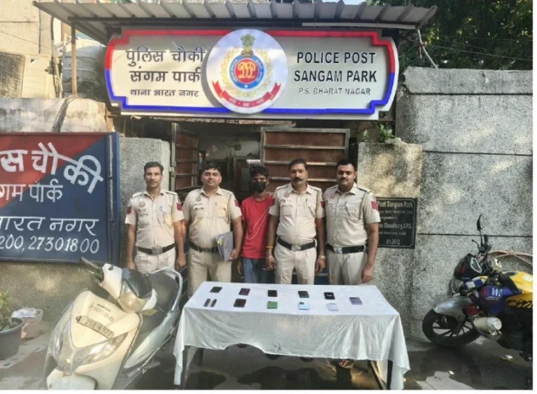 Police officers and a face-covered man with phones and a scooter outside the Sangam Park police post