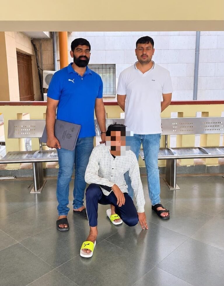 Two standing men with a seated person whose face is pixelated in the supplied police photograph