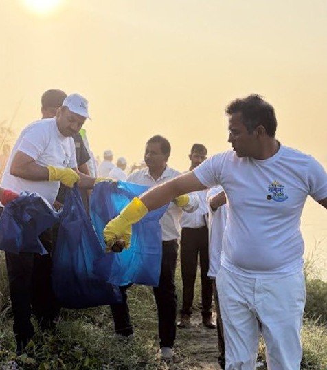Participants wearing gloves collect litter into bags during the Yamuna cleanup in Delhi
