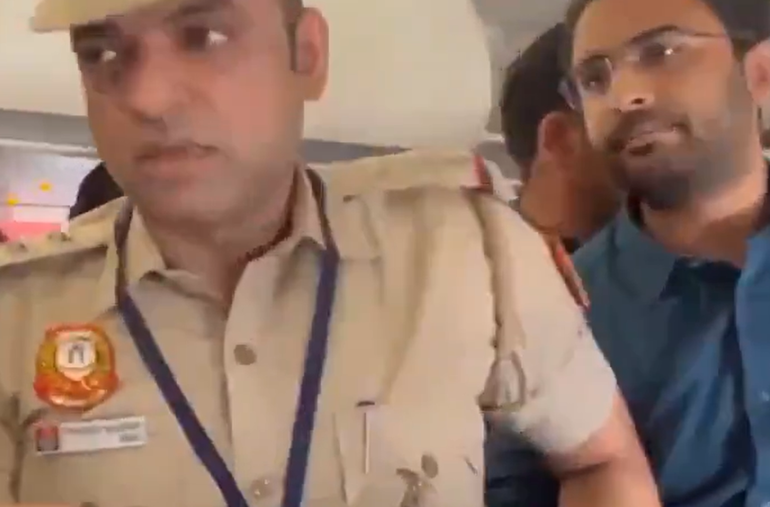 Police personnel and a man wearing glasses inside the aircraft