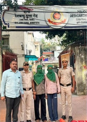 DBG Road Robbery: Three Apprehended, Including Juvenile; Phone Recovered Police personnel with two face-covered people outside Desh Bandhu Gupta Road police station