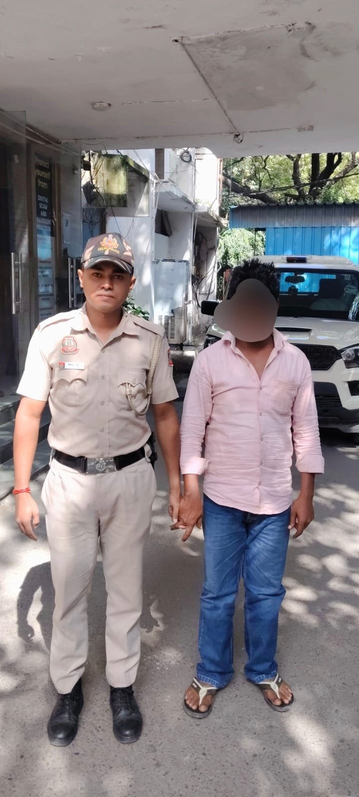 A Delhi Police officer with a man whose face is masked in the supplied ATM-fraud case photograph