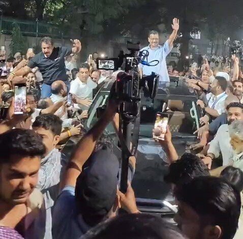 Arvind Kejriwal waves from a car amid a crowd after announcing his release