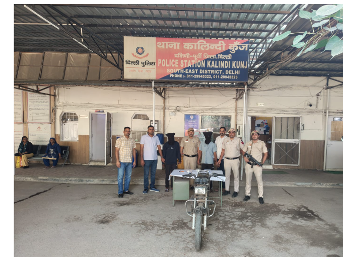 Police personnel with two face-covered men and a motorcycle at Kalindi Kunj police station