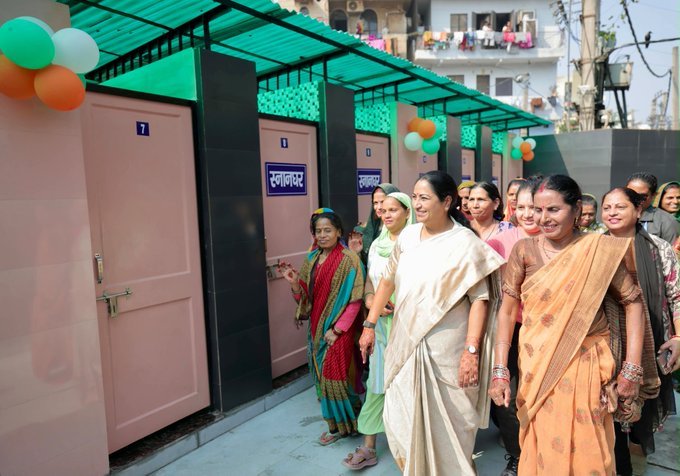 Rekha Gupta walks beside bathing cubicles at a Jan Suvidha Complex during the Shalimar Bagh civic facilities visit